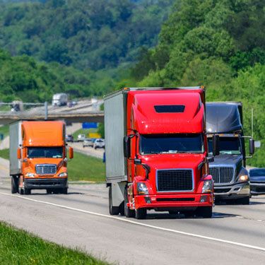 three different colored semi-trucks on highway