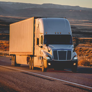 white semi-truck on road at sunset