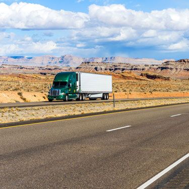 Freight Shipping from Utah to Texas - Green freight truck on highway with cloudy sky