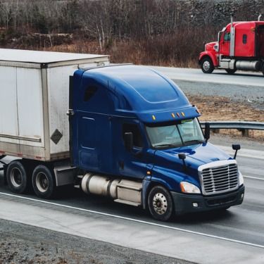 Freight Shipping from Wisconsin to New York - Blue semi truck on highway with red truck in opposite direction