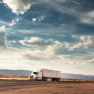 Freight Shipping from Wisconsin to Texas - White truck on highway with dark cloudy sky