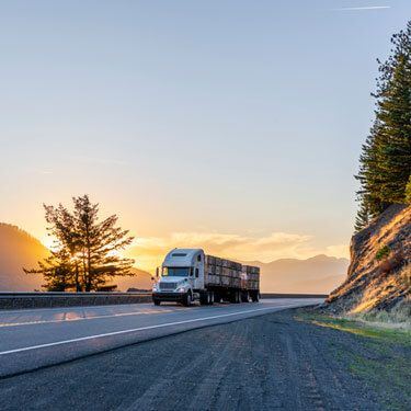 semi-truck on two-lane mountain highway at sunset