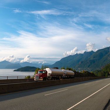 Freight Shipping from Oregon to California - Red freight truck on bridge with cloudy sky