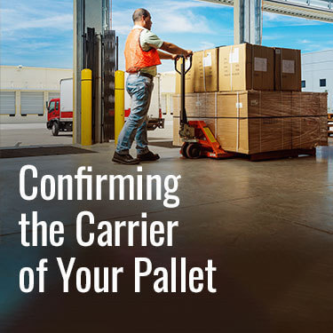 Warehouse worker on a loading dock using a pallet jack to move a pallet with freight stacked on it.