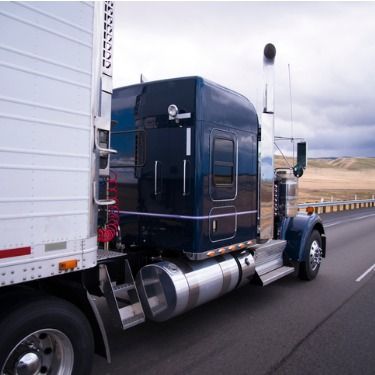 semi-truck driving on highway on cloudy day