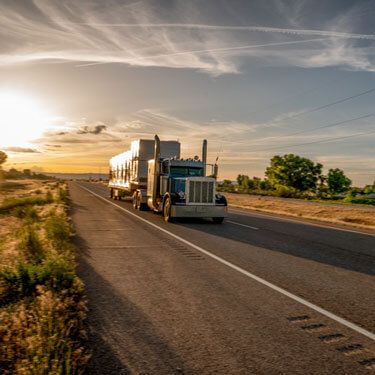 semi-truck driving rural highway at dusk