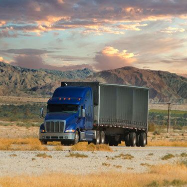 Freight Shipping from Tennessee to California - Blue truck on highway with clouds near mountains