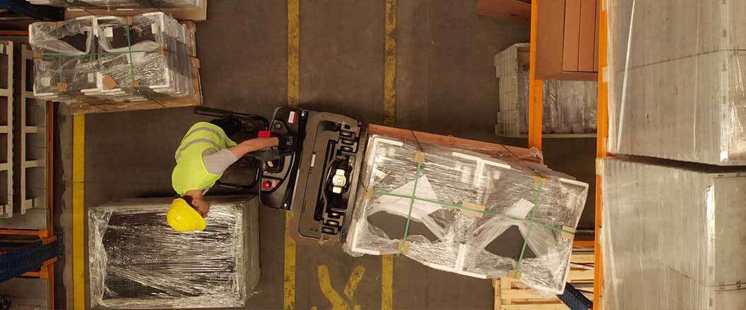 A warehouse worker using a forklift to load a pallet of freight