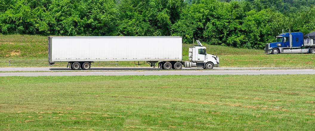 A semi truck traveling on a road near farmland