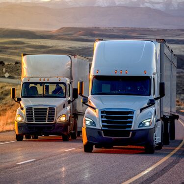 Freight Shipping from Georgia to New York - Two white Semi Trucks on Highway at sunset