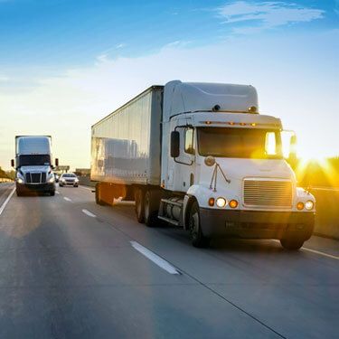 Freight Shipping from Georgia to California - Two white trucks on highway at angle