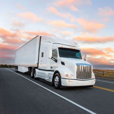 Freight Shipping from Wisconsin to Texas - White truck on highway with light cloudy sky