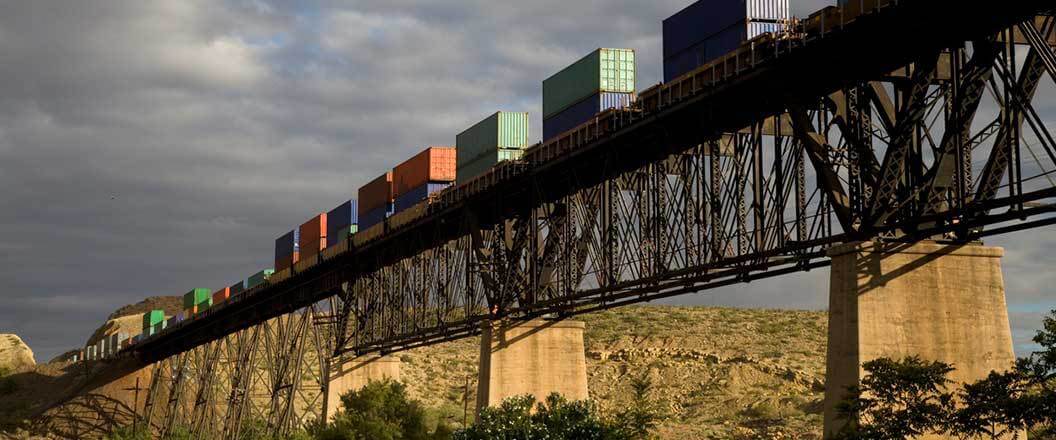 Containers being transported on train tracks going over a bridge